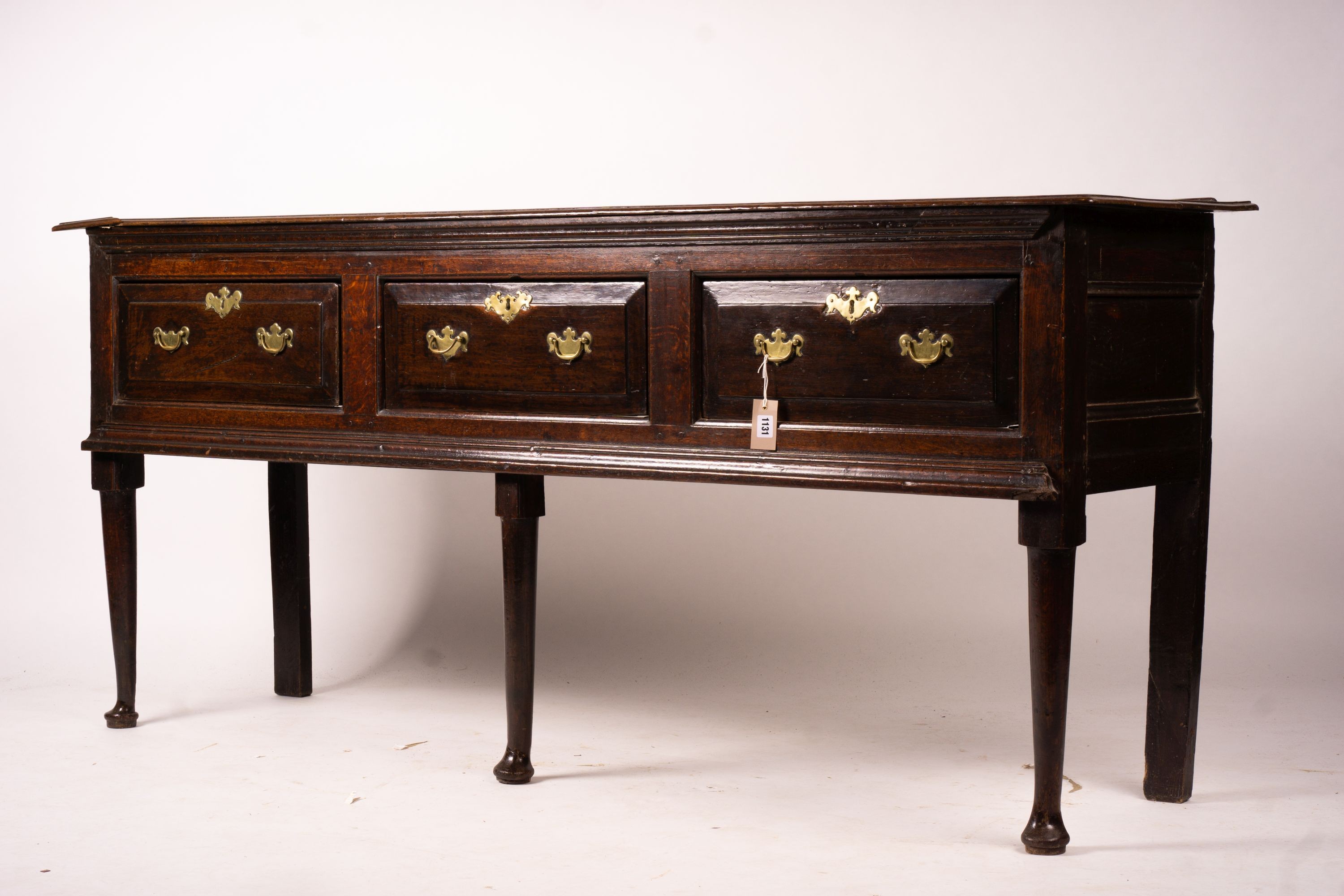 An 18th century oak low dresser on pole turned legs and pad feet, length 198cm, depth 53cm, height 88cm